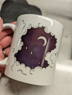 a hand holding a coffee mug with the letter c on it and clouds around it