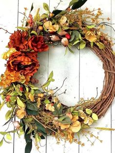 a wreath made out of branches and flowers on a wooden floor with white boards behind it