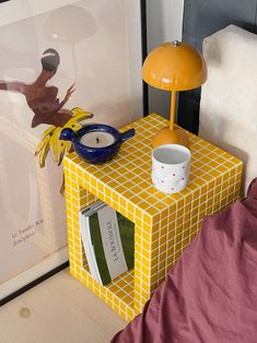 a yellow and white box sitting on top of a bed next to a lamp