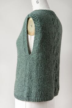 a green knitted sweater with a hole in the middle on a mannequin head