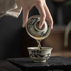 a person pouring water into a bowl with chinese writing on the side and in it