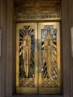 an ornate gold door with two statues on the front and side panels, flanked by a glass window