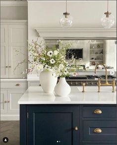 two vases with flowers sit on a kitchen island