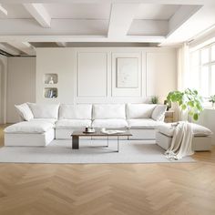 a living room with white furniture and wood floors