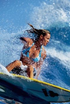 a woman riding a surfboard on top of a wave in the ocean with water splashing around her