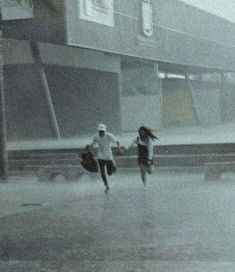 two people running in the rain holding hands