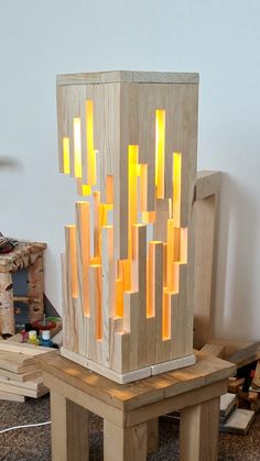 a wooden sculpture with yellow lights on it's sides and a chair in the background