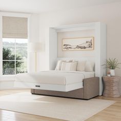 a white bed sitting in a bedroom on top of a hard wood floor next to a window