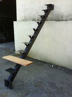 a wooden bench sitting in front of a building with spikes on it's back