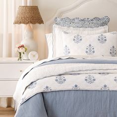 a bed with blue and white bedspread in a bedroom next to a lamp