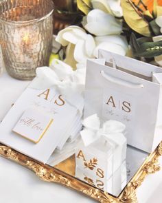 white and gold gift bags on a tray with flowers in the background at a wedding reception