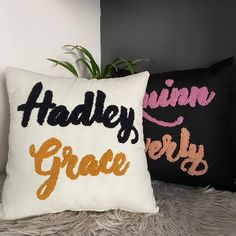 two black and white pillows sitting on top of a fur covered floor next to a plant