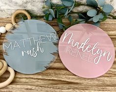 two personalized wooden baby toys on top of a wooden table next to eucalyptus leaves