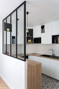 a kitchen with white cabinets and black counter tops is seen through the glass door on the wall