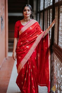 a woman in a red sari is leaning against a wall with her hand on the railing