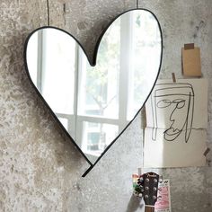 a heart shaped mirror hanging on the side of a wall