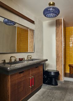 a bathroom with yellow and blue tiles on the walls, two sinks and a black toilet