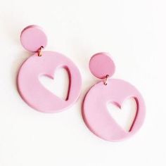 the pink earrings are shaped like a heart and have two circular discs on each ear