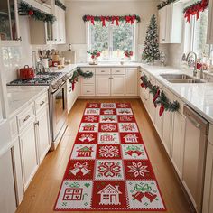 a kitchen decorated for christmas with red and green rugs on the floor, white cabinets and appliances