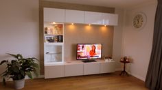 a living room with a large television on the wall next to a potted plant