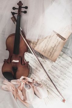 a violin and some sheet music on a bed