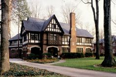 a large brown and white house in the middle of a park with lots of trees