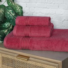 three red towels sitting on top of a wooden table next to a potted plant