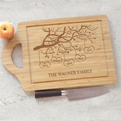 a cutting board with an apple and knife next to it on the table, which has a family tree engraved on it