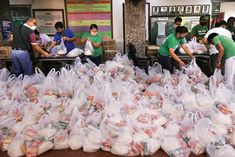 several people are sorting bags of food in the store while others stand around and look at them