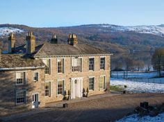 an old stone house with snow on the ground and mountains in the backgroud