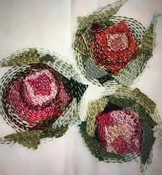 three red and green flowers sitting on top of a white cloth covered tablecloths