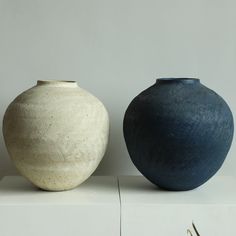 two vases sitting side by side on top of a white shelf next to each other