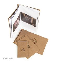 an open photo album sitting on top of a table next to other photos and envelopes