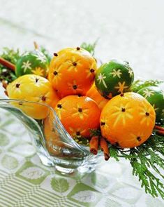 a glass vase filled with oranges on top of a table