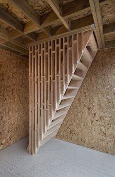 an unfinished room with wooden stairs and plywood walls