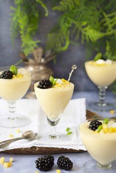 three glasses filled with dessert and topped with blackberries