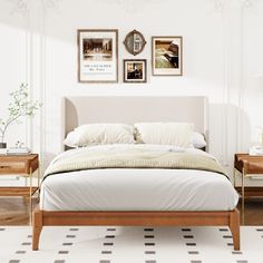 a bed with white sheets and pillows in front of two pictures on the wall above it