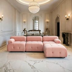 a pink couch sitting in the middle of a living room next to a chandelier