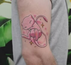 a person with a tattoo on their arm holding a small pink cat in the shape of a mouse