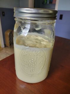 a glass jar filled with liquid sitting on top of a wooden table