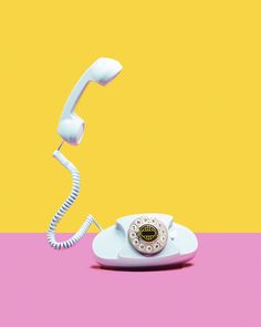 an old fashioned phone sitting on top of a pink and yellow table