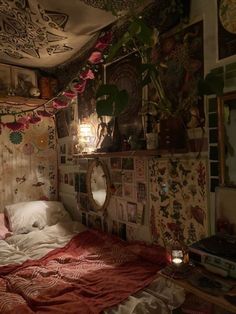 a bedroom with many pictures on the wall and a bed covered in red sheets, pillows and blankets