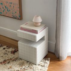 three stacked books on top of each other in front of a window with curtains and rug