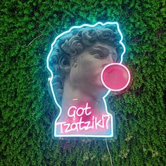 a neon sign that says got tatoatiki on it's side in front of a green wall