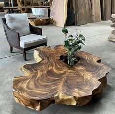 a wooden table sitting on top of a cement floor next to a chair and potted plant