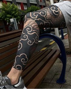 a man sitting on top of a bench next to a wooden bench covered in tattoos