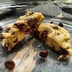 two chocolate chip cookies sitting on top of a metal pan with one broken in half