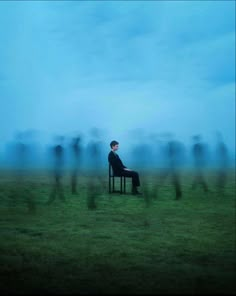 a man sitting on top of a chair in a field