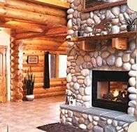 a living room with a stone fireplace and wooden walls