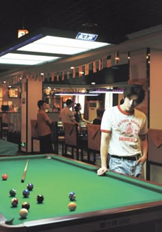 a man standing next to a pool table